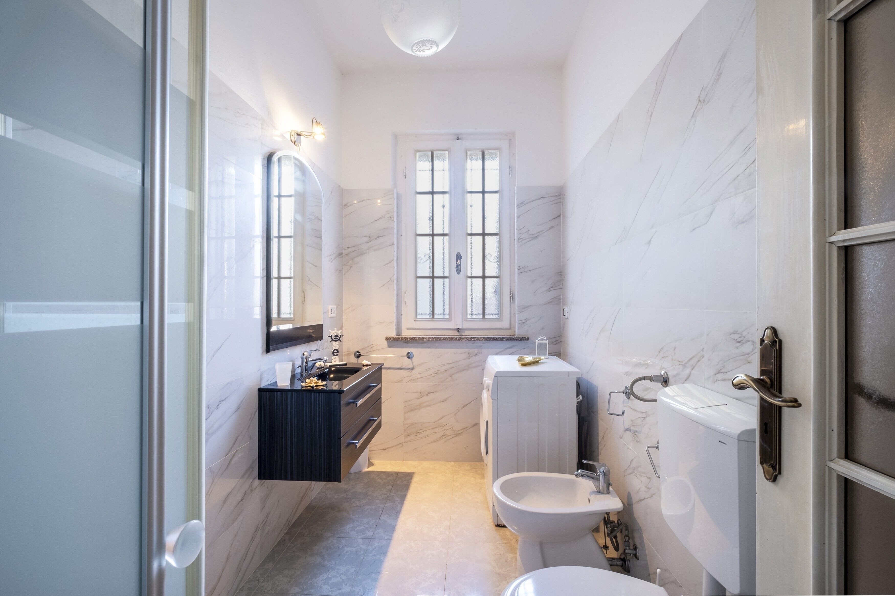 A bathroom with a toilet, bidet, and sink with a mirror.