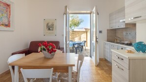 A modern kitchen with a dining area, a view to the outside, and a dining table with chairs. - Holiday Home 'Villa Serèa' with Shared Garden and Air Conditioning (Scala di Furno)