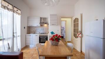 Een koelkast, een oven, een kookplaat, kookgerei, borden en bestek