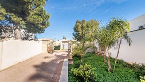 A paved pathway leading to a gated entrance, surrounded by greenery and a white building. - Holiday Home 'Villa Serèa' with Shared Garden and Air Conditioning (Scala di Furno)