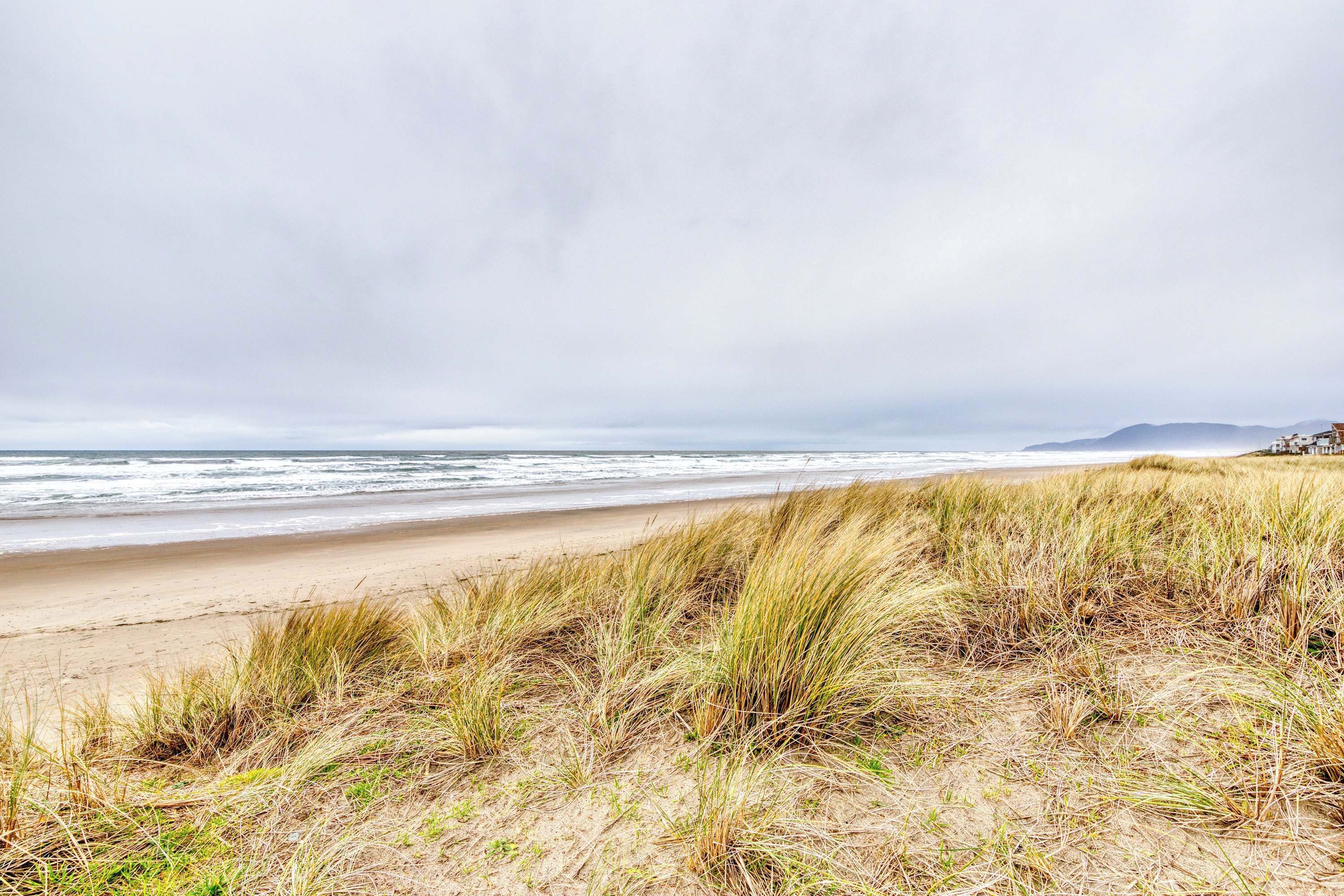A beach with sand dunes and a view of the ocean.