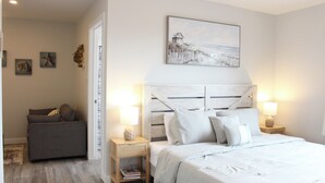 Un dormitorio con cama, mesitas de noche, un sofá y un cuadro en la pared.