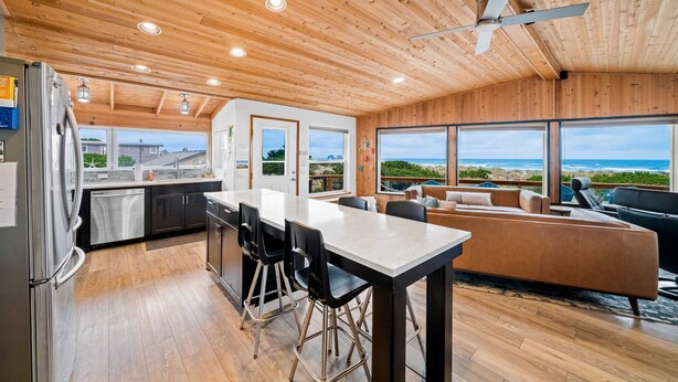 Une cuisine moderne avec un coin repas, un plafond en bois et de grandes fenêtres donnant sur un paysage magnifique.