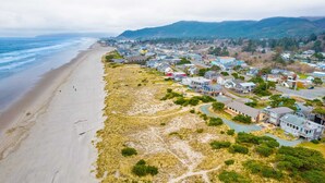 Une ville côtière avec des maisons le long de la plage, une route et des collines en arrière-plan.