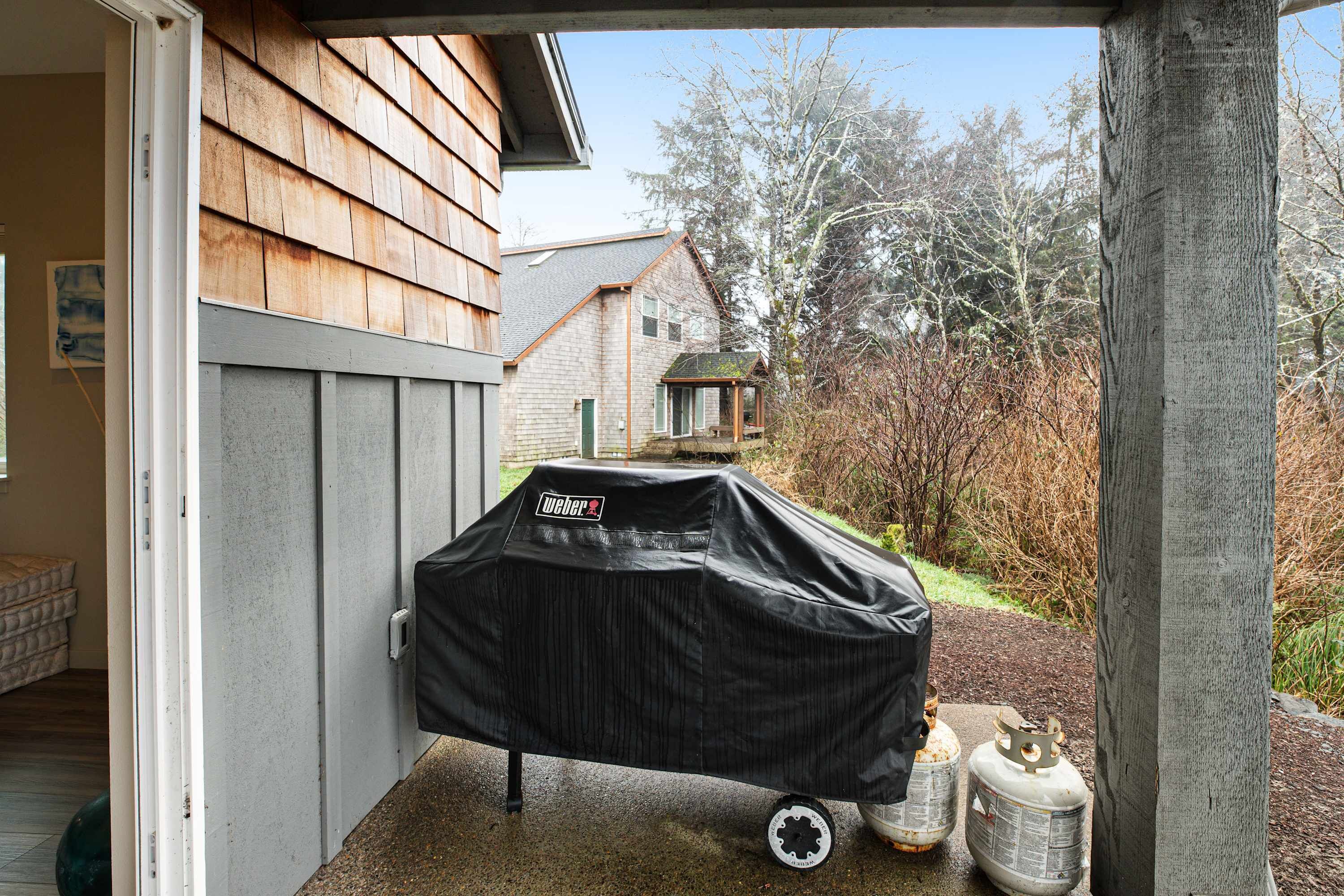 Un barbecue couvert avec des bouteilles de propane à l’extérieur d’une maison.