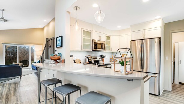 A modern kitchen with a central island, stainless steel appliances, and a bar stool seating area. - New Family Friendly Home with a Furnished Patio and Tranquil Yard (Rockaway Beach)