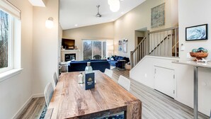 A modern kitchen with a wooden dining table, a built-in oven, and a staircase leading to a loft area. - New Family Friendly Home with a Furnished Patio and Tranquil Yard (Rockaway Beach)