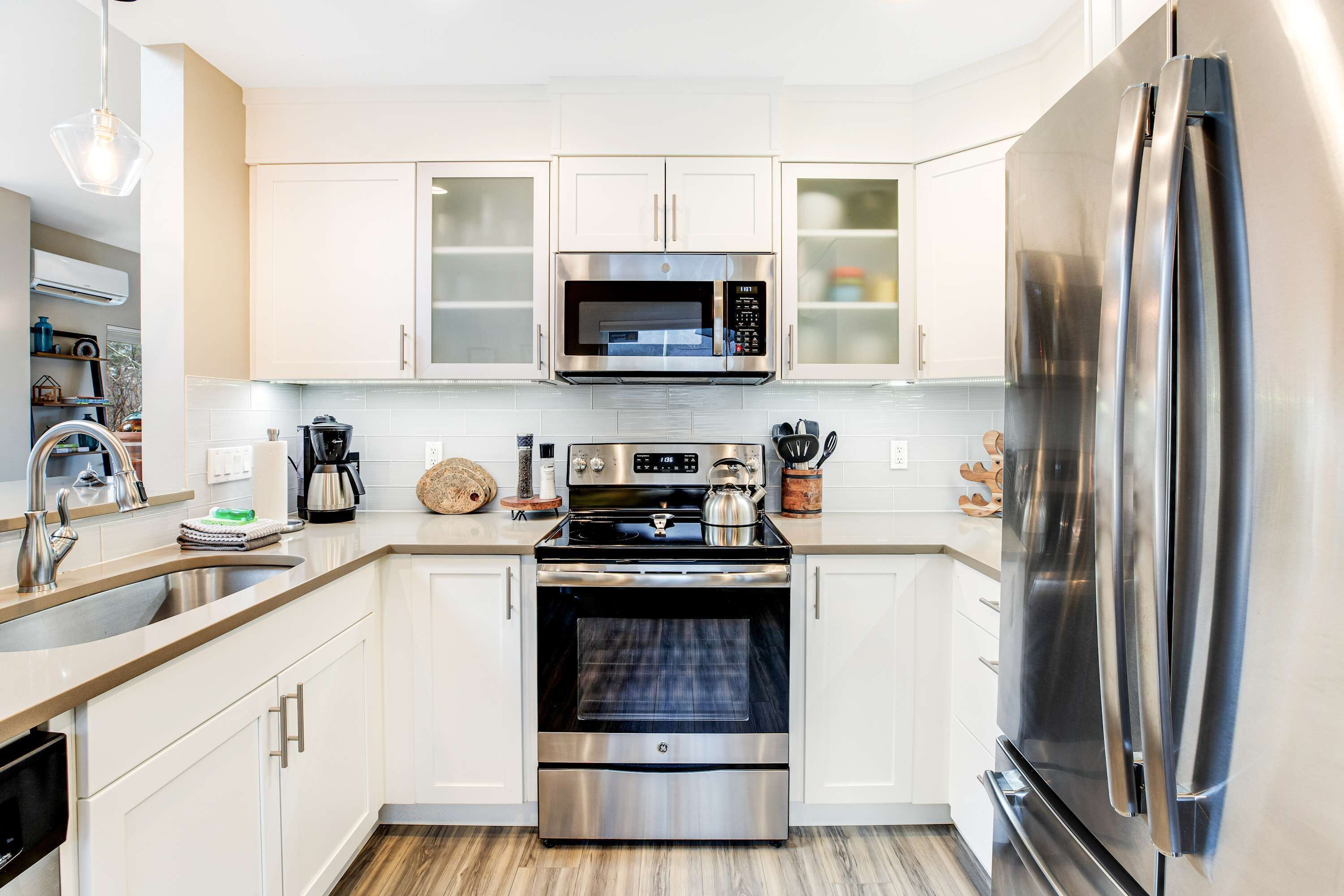 Una cocina moderna con gabinetes blancos, electrodomésticos de acero inoxidable y horno empotrado.