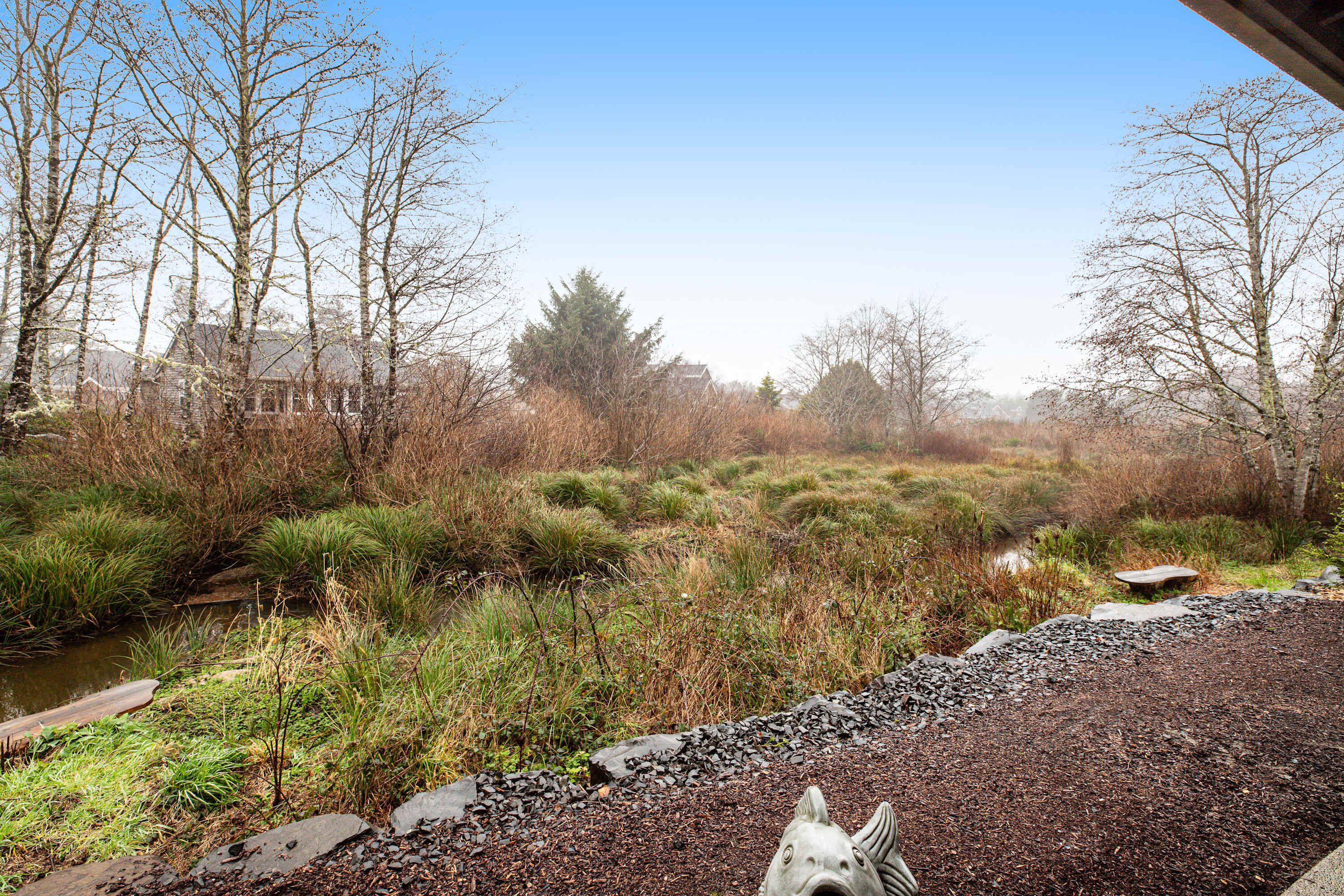 A natural landscape with a pond, trees, and a stone fish sculpture.