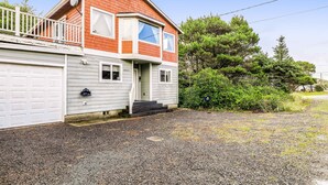 Ein zweistöckiges Haus mit Garage, Veranda und Auffahrt mit Kies.