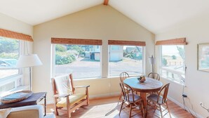 Comedor con mesa y sillas, ventanas amplias con persianas, lámpara y vista al exterior.