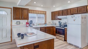 Una cocina con armarios de madera, un refrigerador blanco, una estufa y una cafetera.