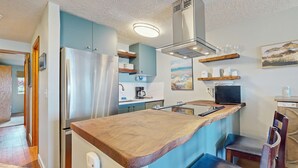 Een moderne keuken met een houten kookeiland, roestvrijstalen apparatuur en een ingebouwde kookplaat.