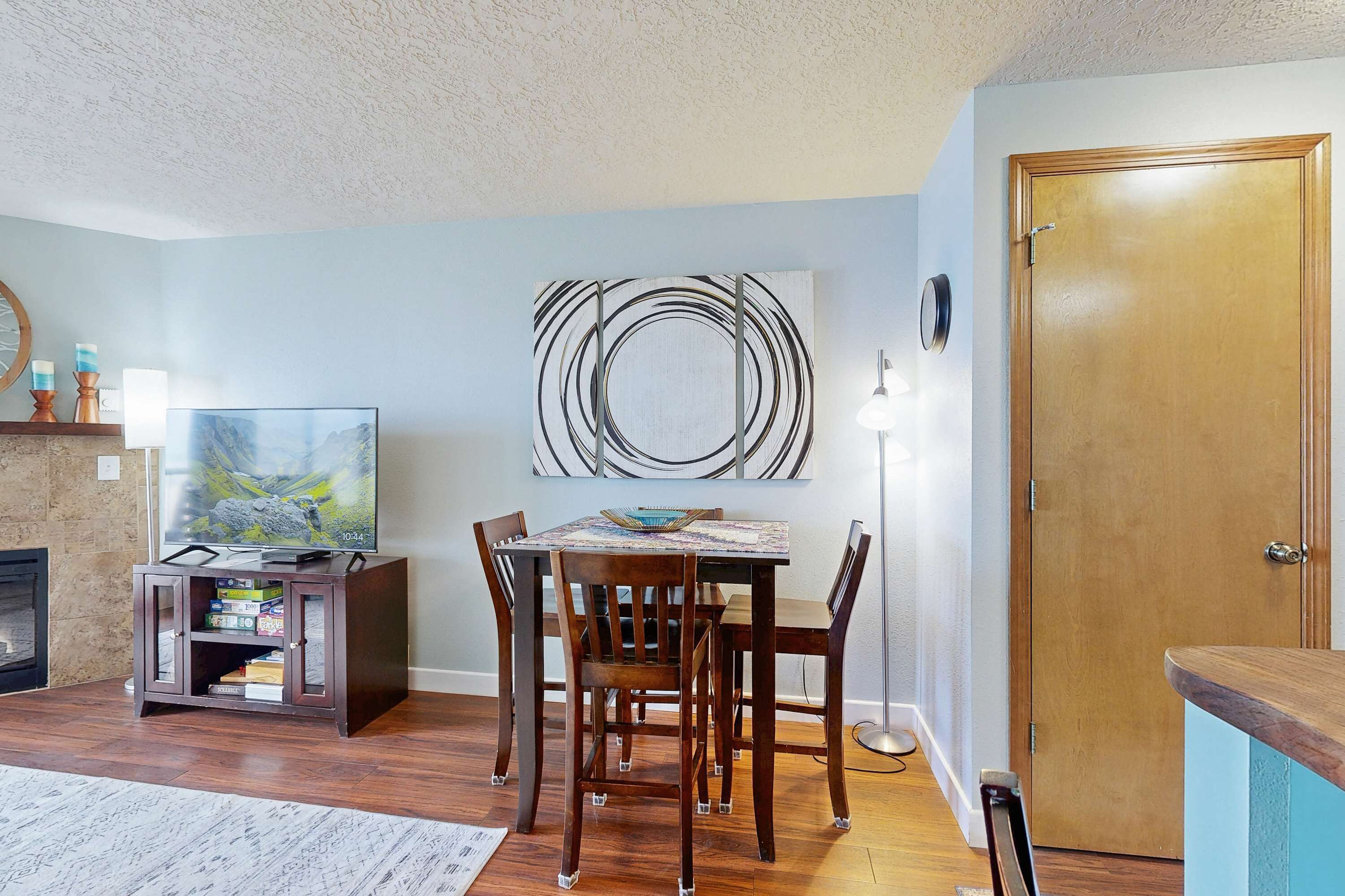 A dining area with a wooden table and chairs, a television, and a fireplace.