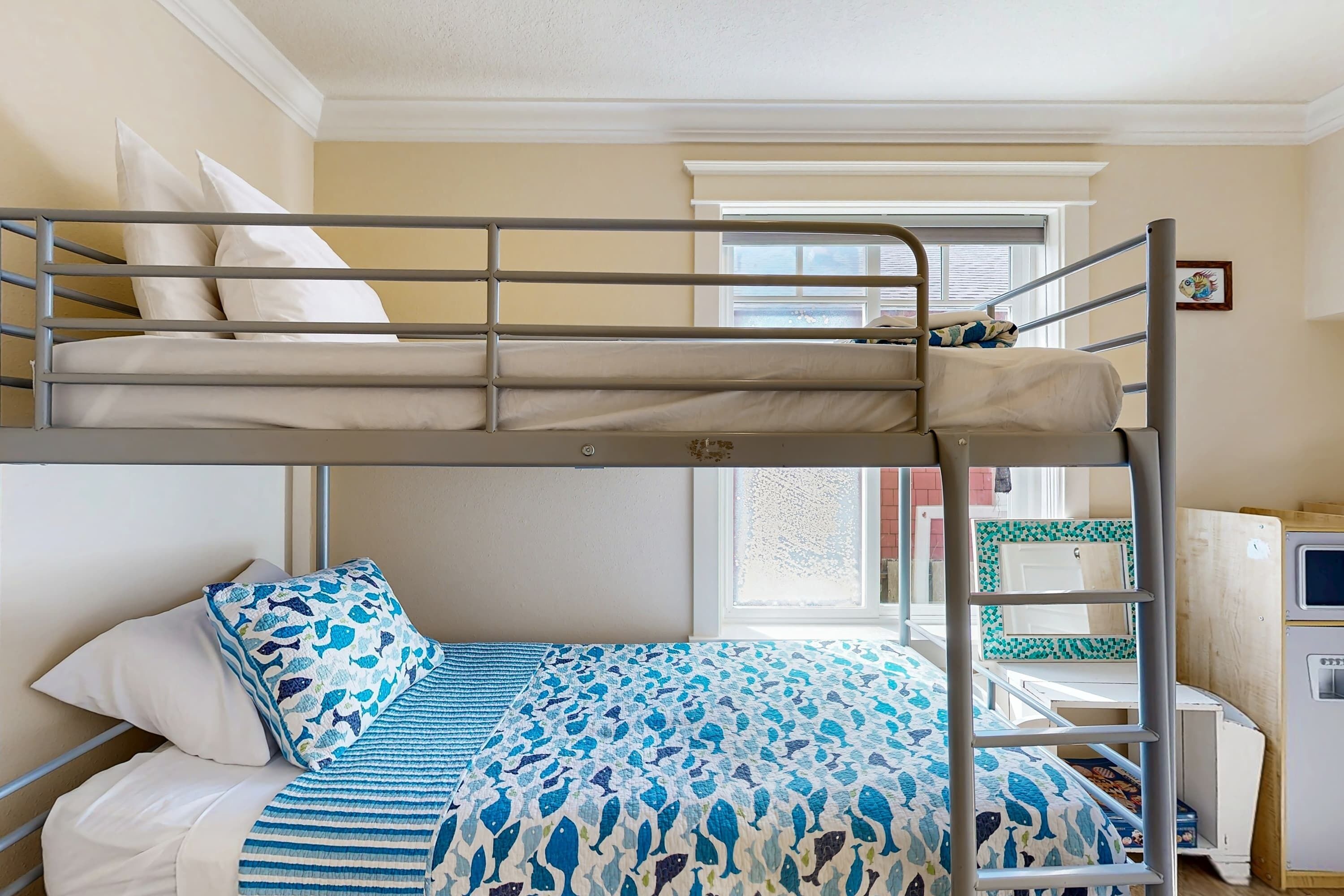 A bunk bed room with a window, a desk, and a chair.