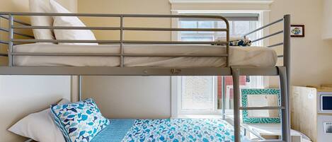 A bunk bed room with a window, a desk, and a chair.