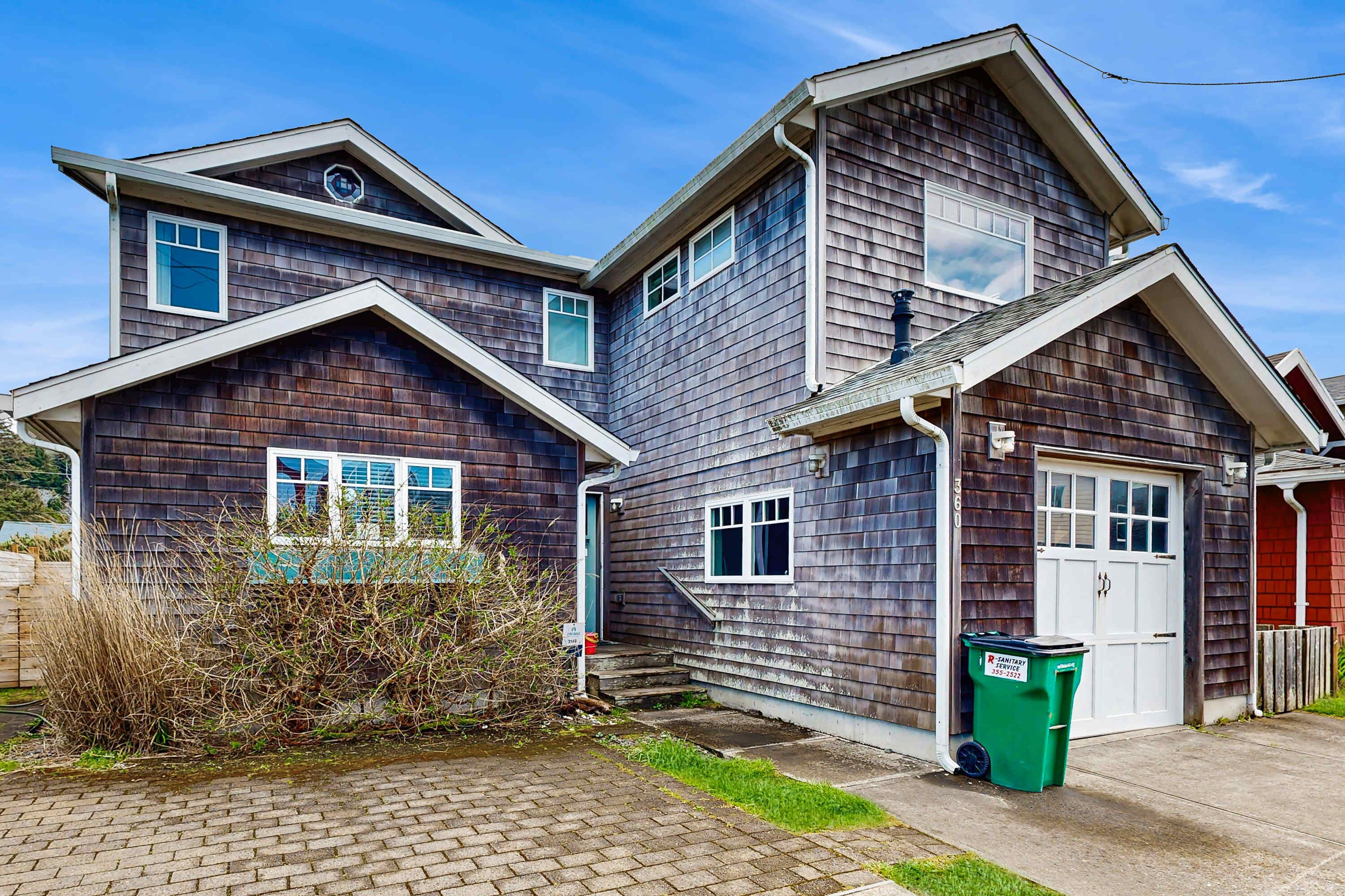 A two-story residential house with a brick driveway, a front door, and a garage.