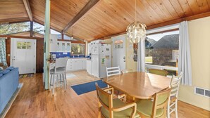 A spacious kitchen with wooden cabinets, a dining table with chairs, and a large window offering a view of the outdoors.