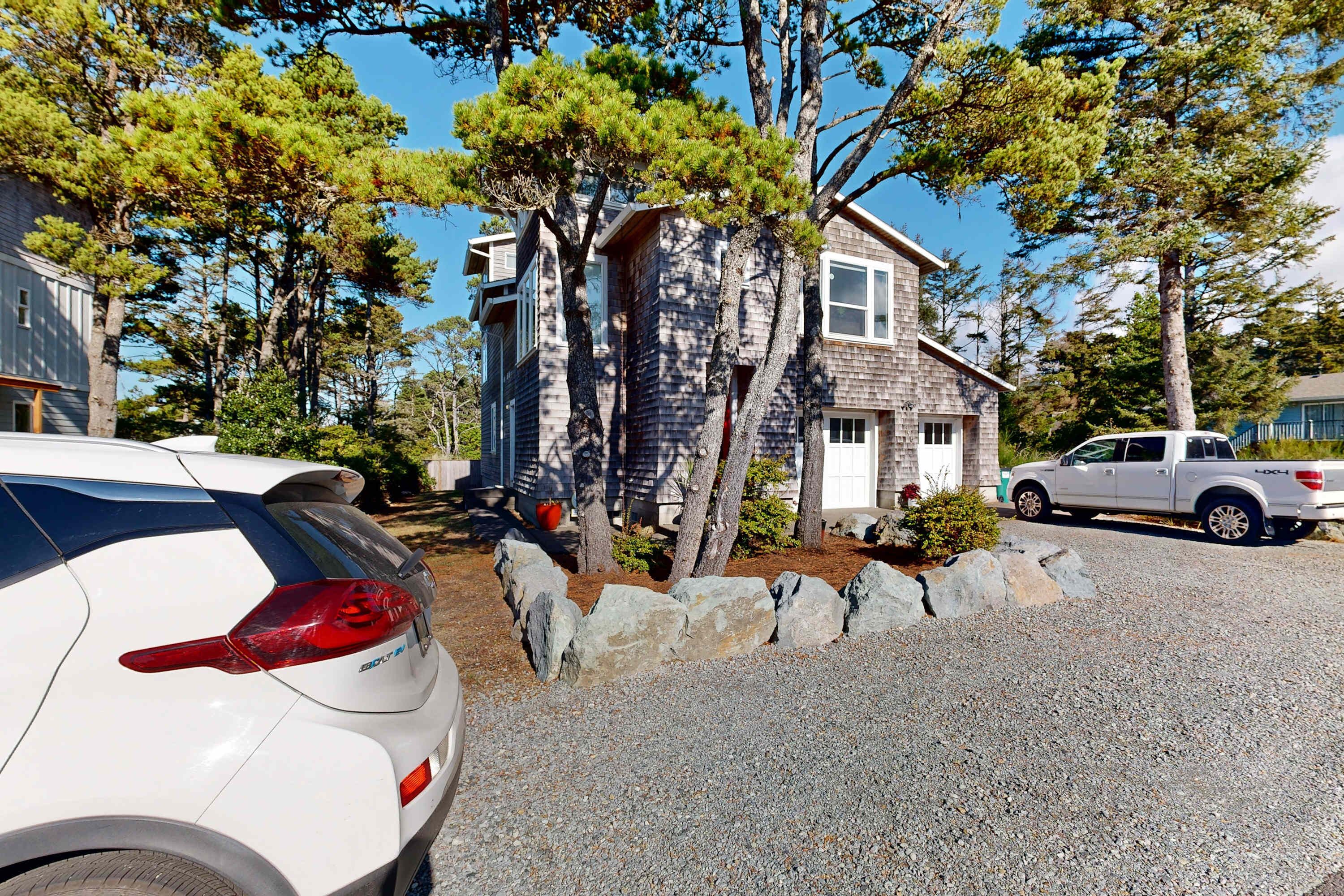 A residential area with houses, a white car, and a pickup truck parked on a gravel driveway.