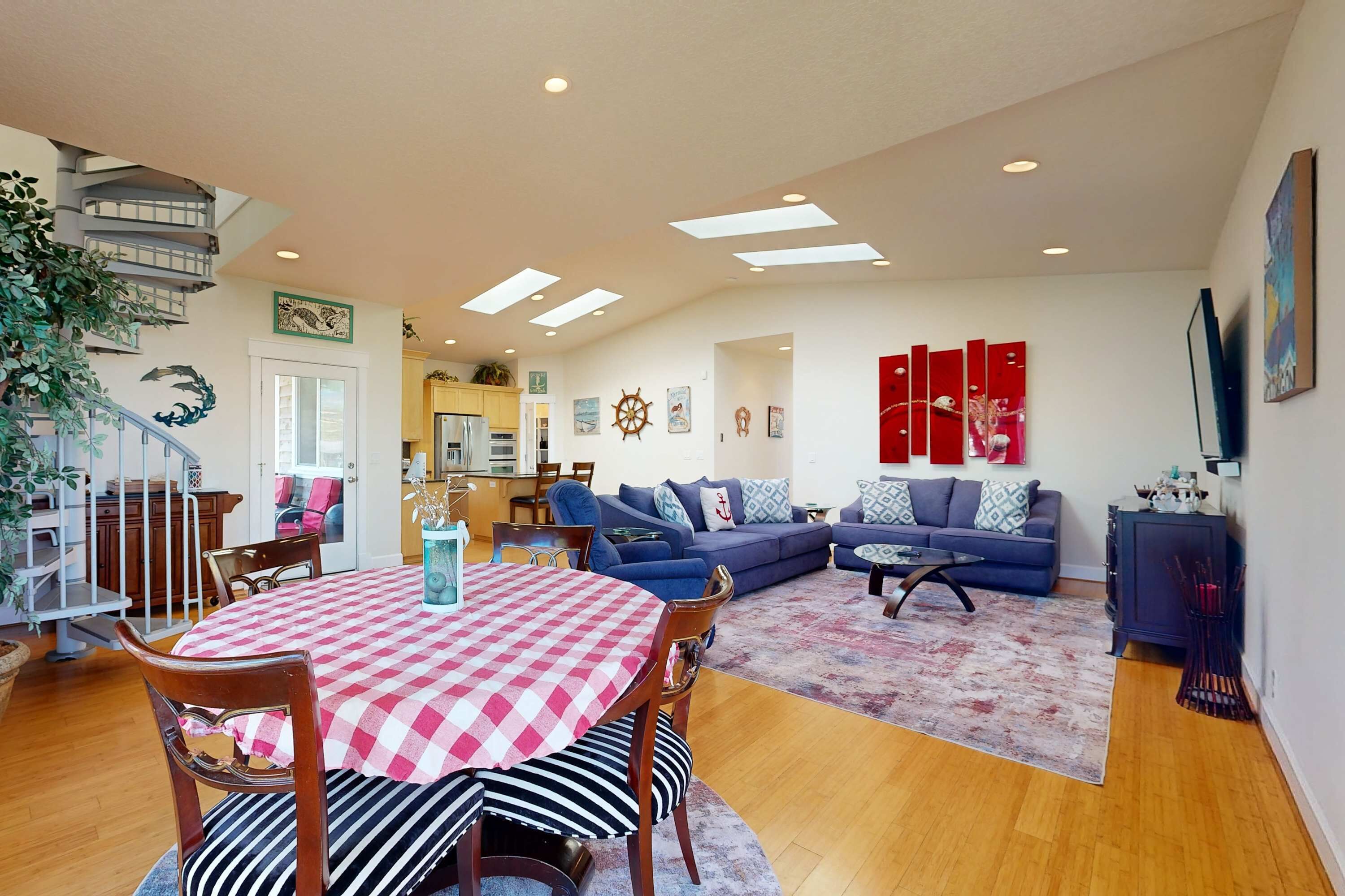 A spacious living area with a dining table, blue sofa, and a staircase leading to an upper floor.