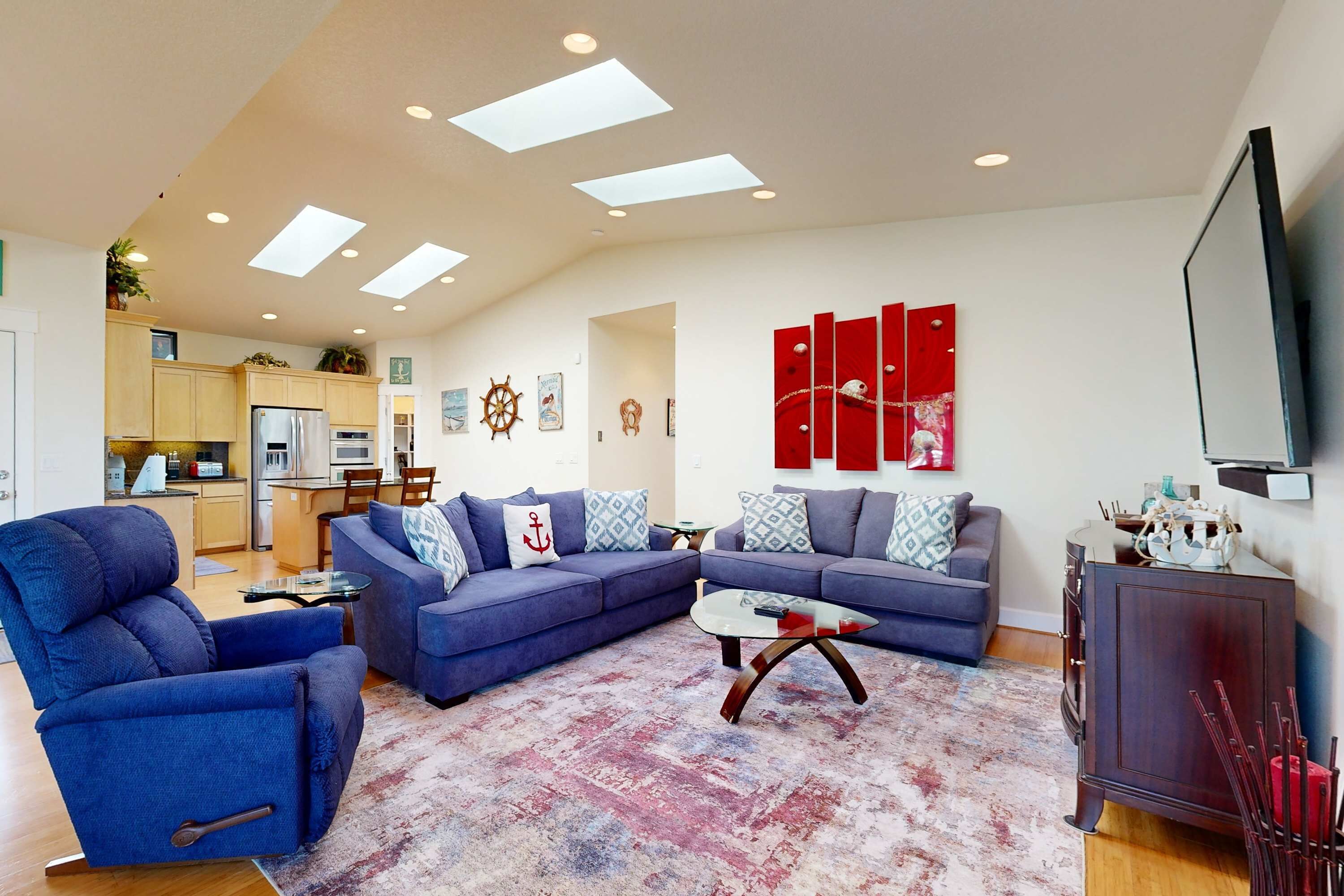 A modern living room with a sectional sofa, a blue armchair, a glass coffee table, and a red accent wall.