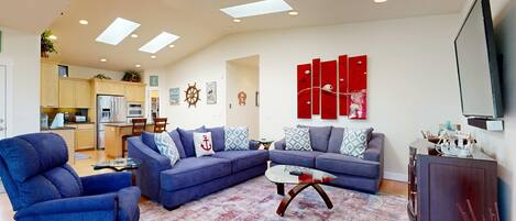 A modern living room with a sectional sofa, a blue armchair, a glass coffee table, and a red accent wall.