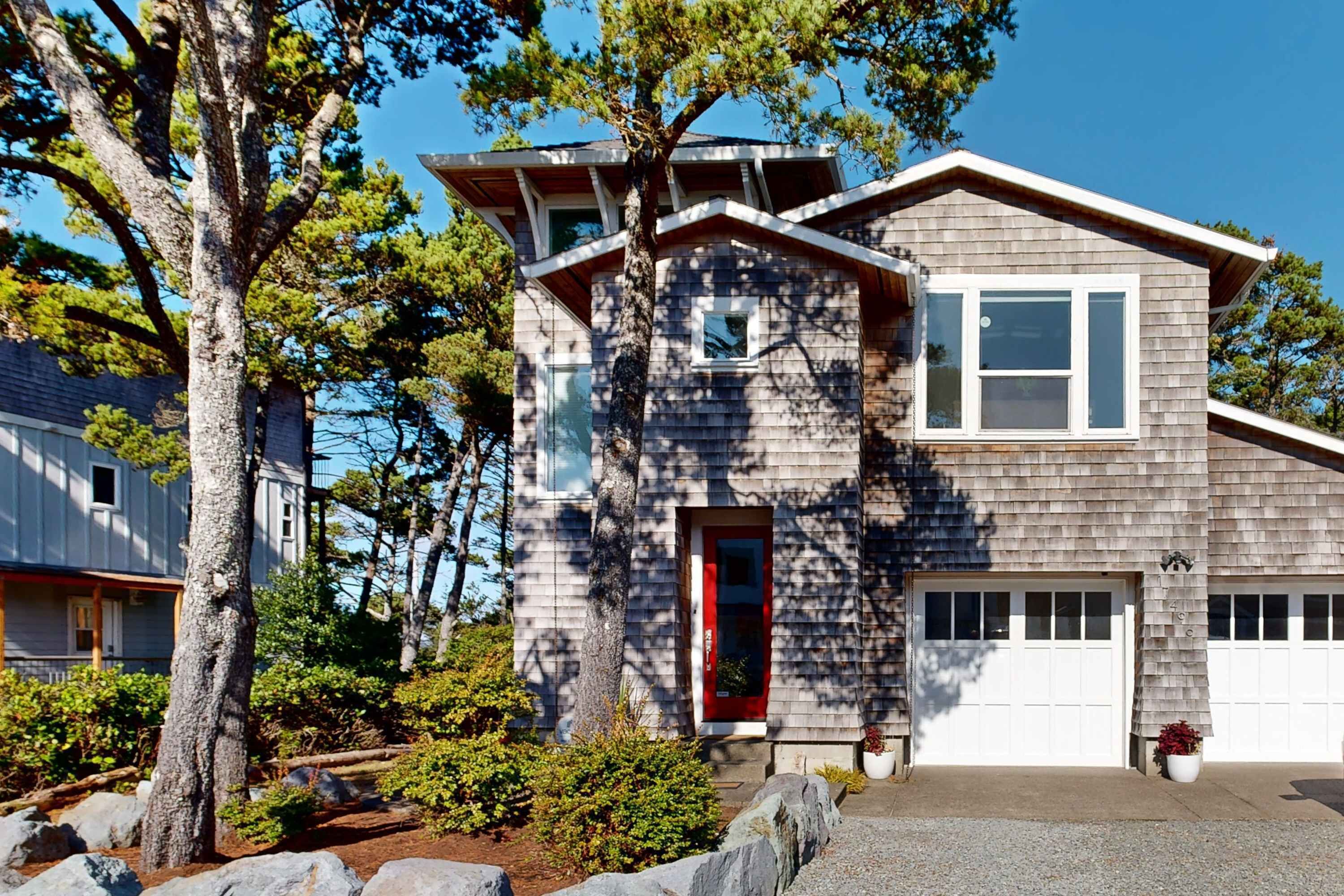 A modern two-story house with a red door, large windows, and a garage.