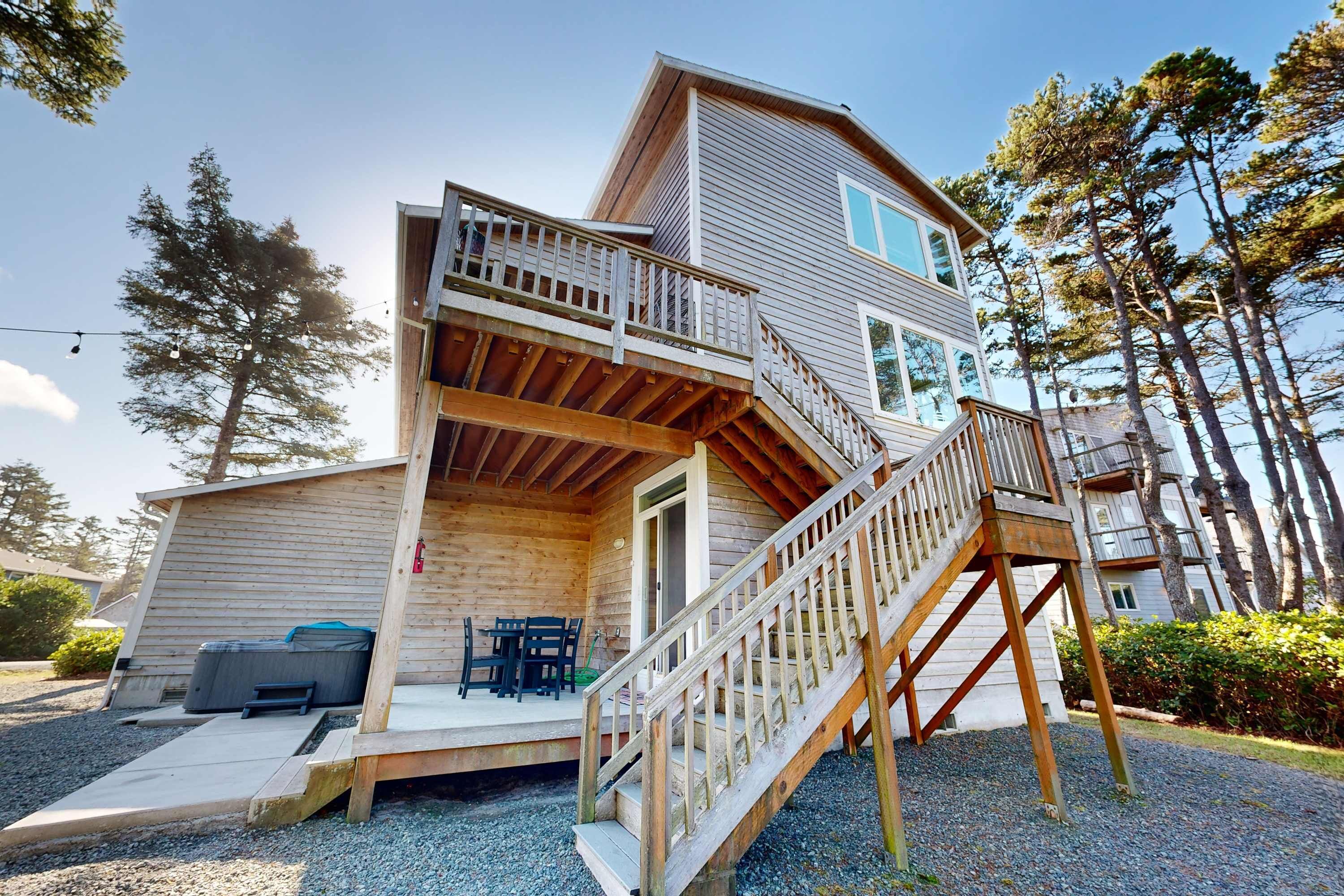 A two-story wooden cabin with a balcony, outdoor seating, and a staircase.