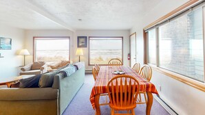 A dining area with a table and chairs, a sofa, and large windows with a view. - Oceanfront Home with Great Ocean View Deck Fireplace Beach Access 2 Dogs OK (Rockaway Beach)