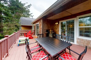 Une terrasse extérieure avec une plateforme en bois, une table à manger avec des chaises et un barbecue.