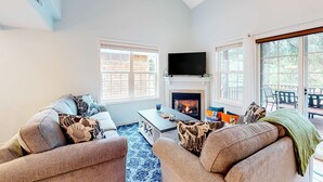 Una sala de estar con chimenea, dos sofás, una mesa de centro y un televisor.