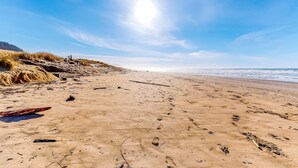 Una playa arenosa con huellas y un trozo de madera a la orilla.