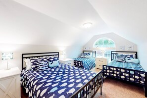 Une chambre avec deux lits, un bureau et une fenêtre donnant sur un paysage verdoyant.