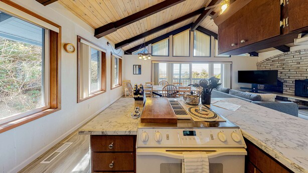 A kitchen with a large island, wooden beams, a TV, and a fireplace.