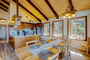 Una cocina amplia con armarios de madera, una isla central y un comedor con una mesa larga y sillas.
