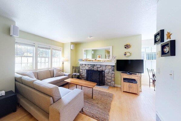 A living room with a sofa, a coffee table, a fireplace, and a television.