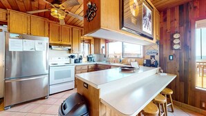 Una cocina moderna con armarios de madera, electrodomésticos de acero inoxidable y una isla central con taburetes.