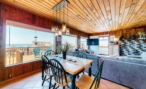 A wooden interior with a dining area, a sofa, and a view of the sea. - Rustic chic treasure with deck grill wood stove outdoor shower dogs ok (Rockaway Beach)