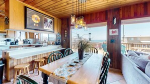 Un interior de madera con comedor, cocina y vistas al mar.