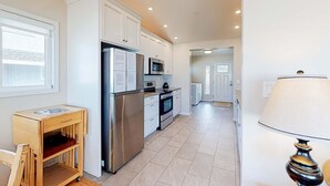 Una cucina moderna con mobili bianchi, elettrodomestici in acciaio inossidabile e un tavolino in legno.