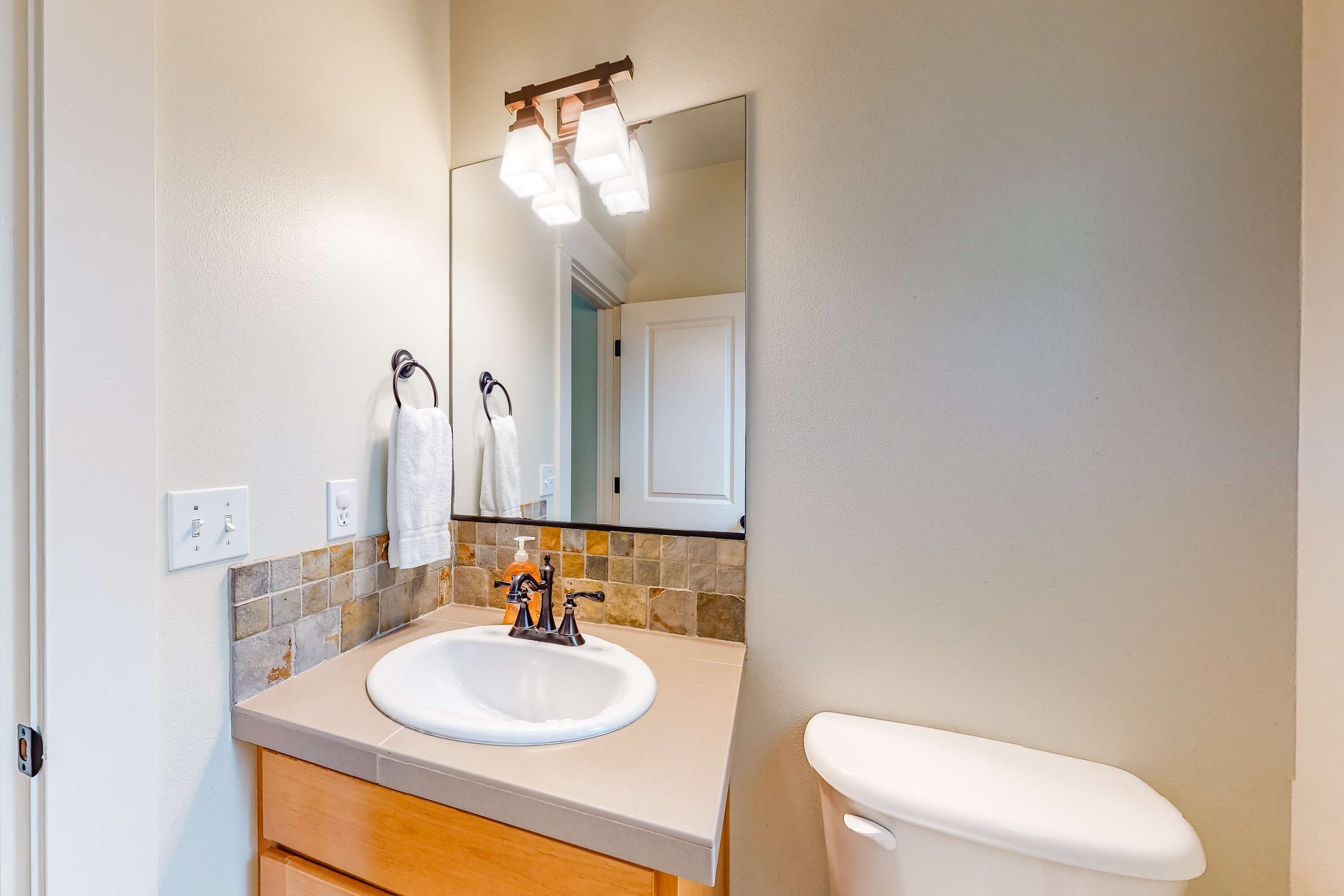 A bathroom with a white sink, a mirror, and a toilet.