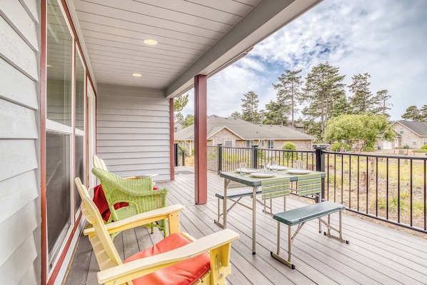 A covered porch with outdoor furniture, a view of the neighborhood, and a clear sky.