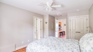 A bedroom with a bed, a ceiling fan, and a view into the kitchen area. - Spacious coastal retreat | 3-min walk to beach | Decks & mountain views (Rockaway Beach)