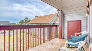 A covered balcony with a red railing, a white door, and two wicker chairs. - Spacious coastal retreat | 3-min walk to beach | Decks & mountain views (Rockaway Beach)