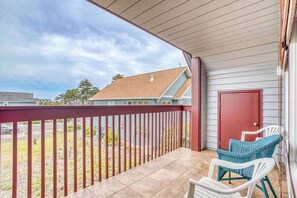 A covered balcony with a red railing, a white door, and two wicker chairs. - Spacious coastal retreat | 3-min walk to beach | Decks & mountain views (Rockaway Beach)
