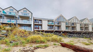 Un hôtel situé en bord de mer, doté de nombreux balcons, d’une plage de sable et d’une côte rocheuse.