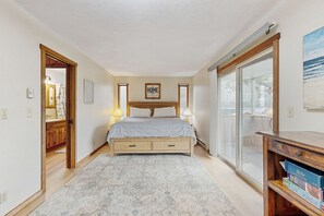 A bedroom with a bed, bedside lamps, a wooden headboard, a large window, and a view of the outdoors. - Oceanfront home with great views high speed WiFi and direct beach access (Rockaway Beach)