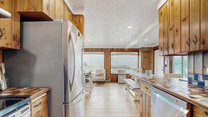 A modern kitchen with wooden cabinets, stainless steel appliances, and a view to the outside. - Oceanfront home with great views high speed WiFi and direct beach access (Rockaway Beach)