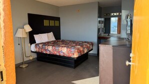 A bedroom with a bed, bedside lamp, and a dresser.