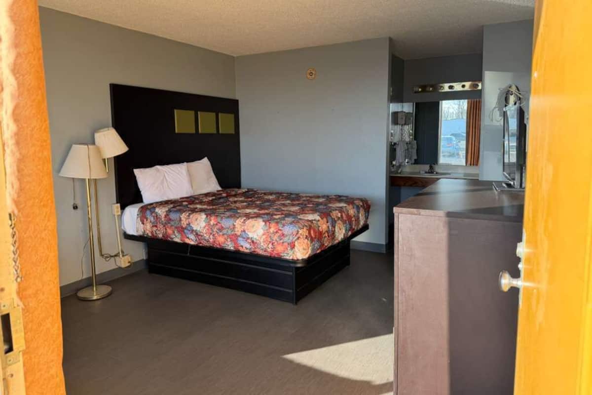 A bedroom with a bed, bedside lamp, and a dresser.